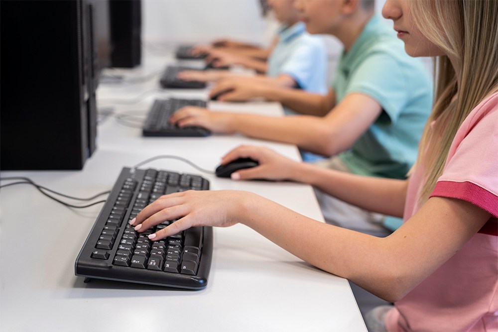 Alunos usando computador em laboratório de informática na escola.