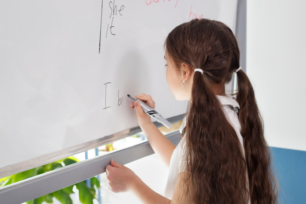 Menina escrevendo em um quadro branco com um marcador