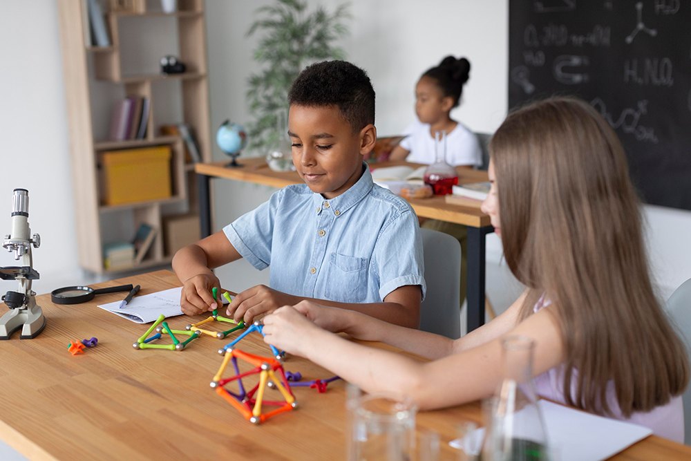 Crianças do ensino fundamental brincando com jogo de peças para aprender química.