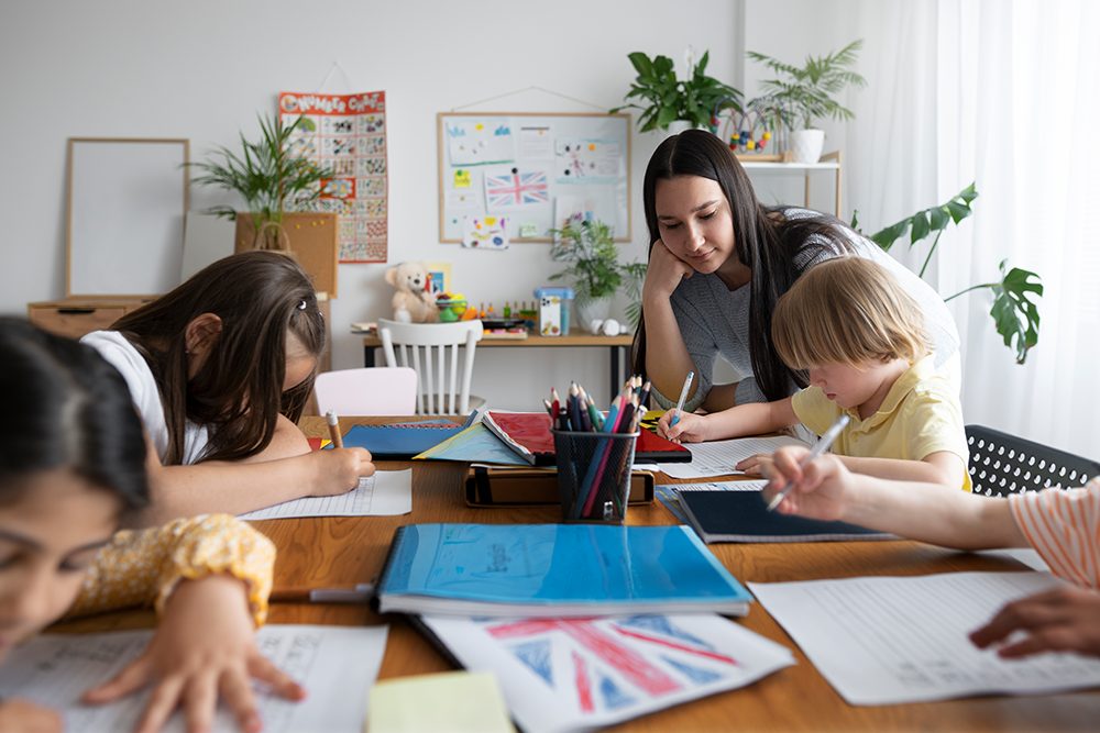 Professora de inglês tirando dúvidas de seus alunos em sala de aula.