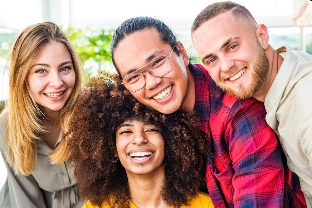 Grupo de jovens adultos sorrindo e posando para a câmera, simbolizando diversidade e amizade.